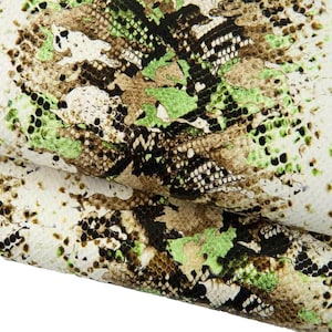 Könnte beinhalten: Nahaufnahme eines strukturierten Materials mit Schlangenmuster. Das Design weist eine Mischung aus Farben auf, darunter Weiß, Grün, Braun und Schwarz, wodurch ein reptilienartiges Aussehen entsteht. Das Material scheint gefaltet zu sein.