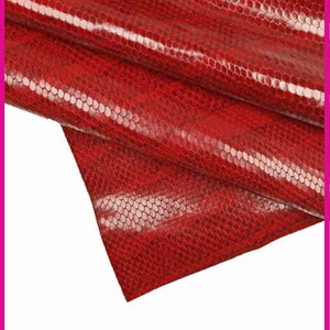 May include: Red snakeskin fabric with a textured, scaly pattern. The fabric is folded and draped, showing the texture and sheen.