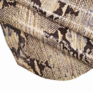 Könnte beinhalten: Nahaufnahme eines braunen und weißen Schlangenlederstoffs mit einem strukturierten Muster.