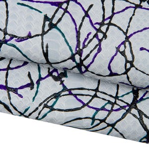 May include: Close-up of a textured white fabric with a repeating scale pattern. The fabric is overlaid with a network of abstract lines in black, teal, and purple, creating a modern, artistic design. The fabric is folded over.