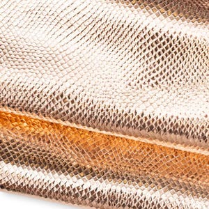 May include: A metallic rose gold material featuring a repeating, raised diamond-shaped scale pattern. The surface has a reflective, glossy finish that catches the light, creating highlights and shadows across the textured, snake-like skin design.