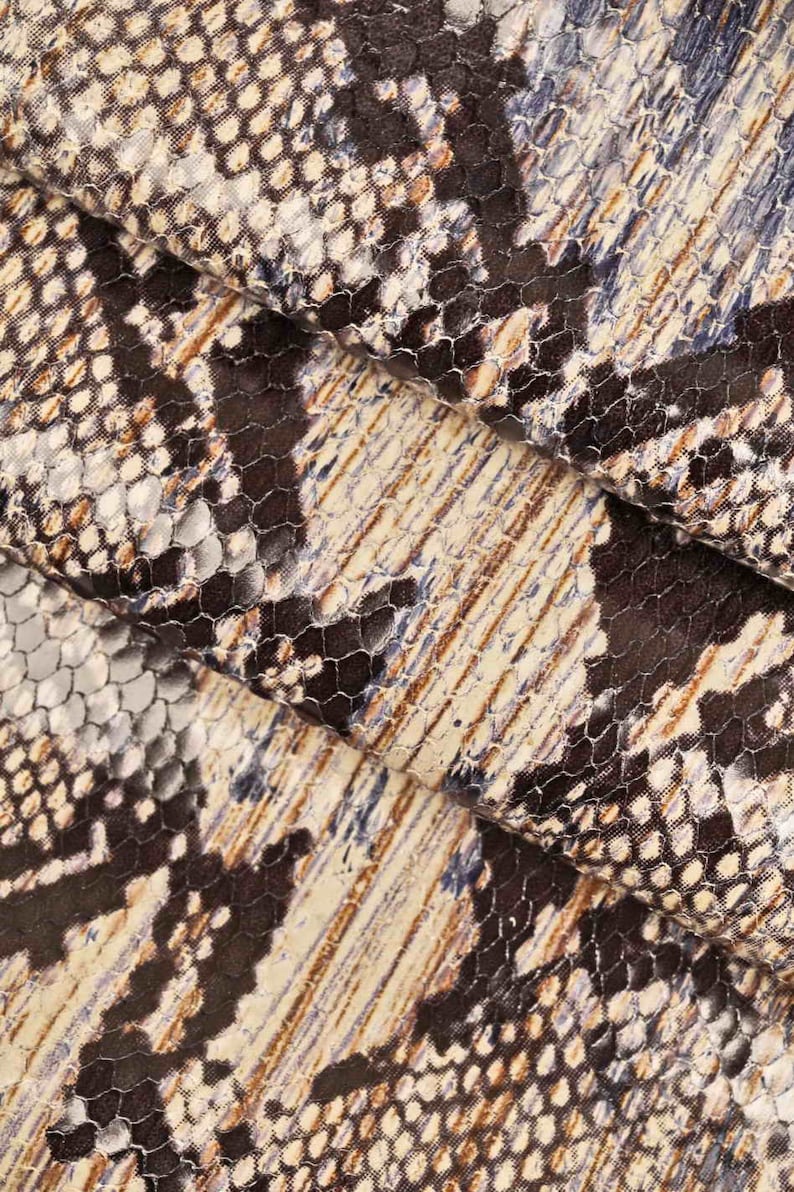 Op de afbeelding: Close-up van een stof met een slangenhuidpatroon in tinten bruin, beige en blauw.