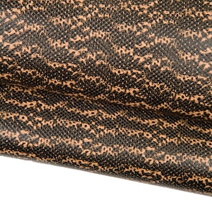 Peut inclure: Gros plan sur une matière texturée avec un motif de taches et de lignes noires et beiges. La matière semble pliée, révélant les variations de texture et de couleur. Le motif ressemble à une peau de reptile.