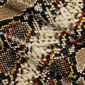 Pode incluir: Close-up de um tecido com padr&atilde;o de pele de cobra. O tecido &eacute; marrom, preto, vermelho e amarelo. O padr&atilde;o &eacute; composto por pequenos quadrados.