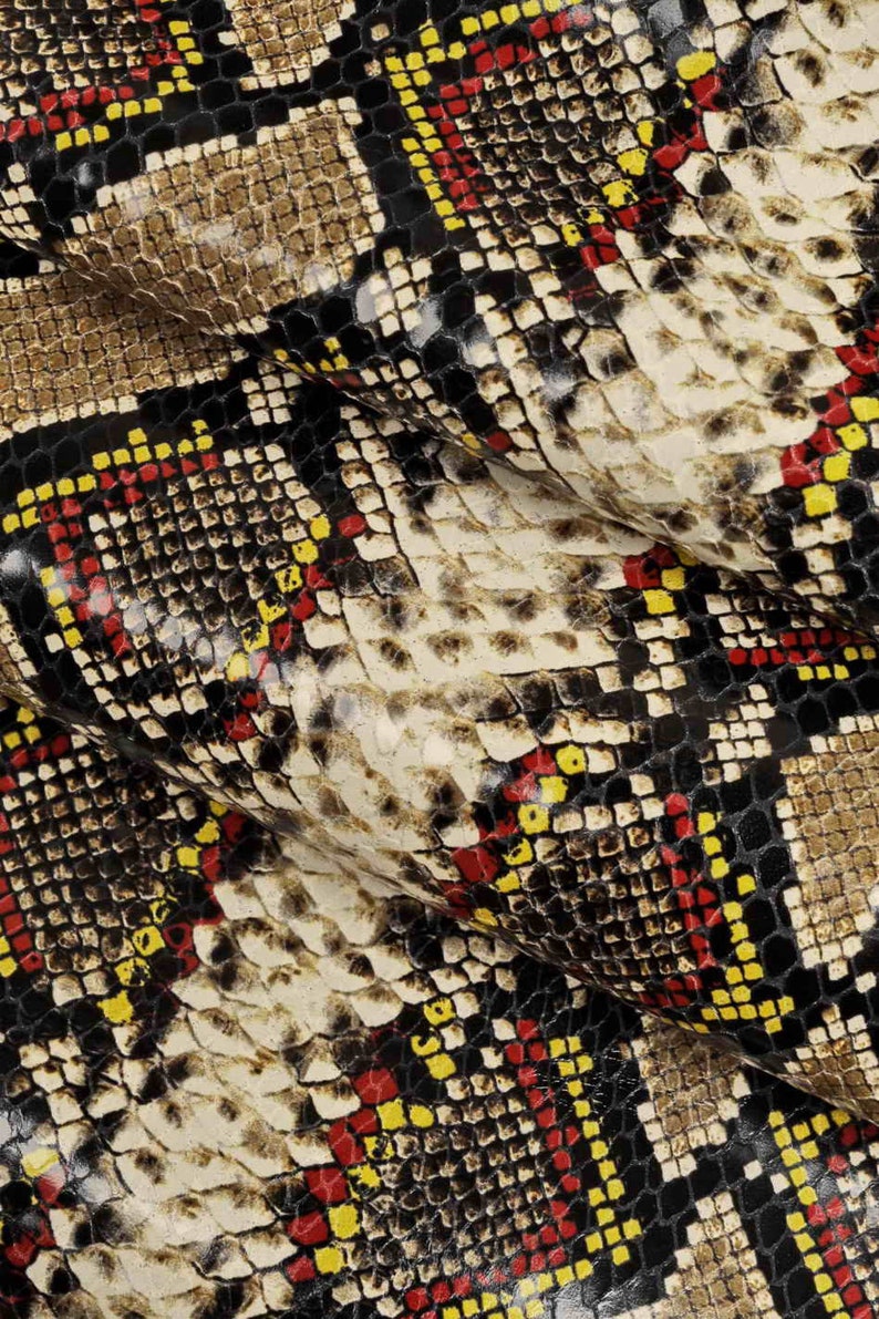 Pode incluir: Close-up de um tecido com padr&atilde;o de pele de cobra. O tecido &eacute; marrom, preto, vermelho e amarelo. O padr&atilde;o &eacute; composto por pequenos quadrados.