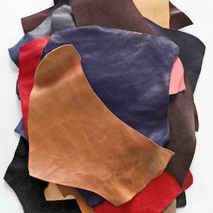 Pode incluir: Um monte de sobras de couro em v&aacute;rias cores, incluindo marrom, vermelho, azul e bege. O couro est&aacute; disposto em um padr&atilde;o aleat&oacute;rio, com algumas pe&ccedil;as sobrepostas a outras. A palavra "random" est&aacute; escrita em letras cor-de-rosa na parte superior da imagem.