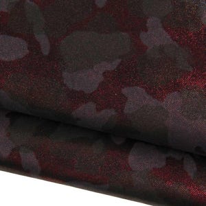 Può includere: Un tessuto con un motivo mimetico scuro con forme nero profondo e grigio antracite sovrapposte a una base rossa metallizzata vibrante e scintillante. Il materiale ha una consistenza liscia e riflettente con una lucentezza distinta.