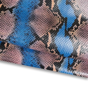 Könnte beinhalten: Nahaufnahme eines Schlangenhautmusters in Blau-, Rosa-, Schwarz- und Beigetönen. Das Design weist eine schuppenartige Textur auf, wobei sich die Farben vermischen und überlappen, um einen realistischen Reptilienhaut-Effekt zu erzeugen. Das Muster wird wahrscheinlich für Mode- oder Dekorationszwecke verwendet.