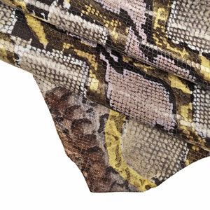 May include: Close-up of a snakeskin fabric with a brown, black, yellow, and pink pattern.