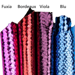 Könnte beinhalten: Nahaufnahme von vier Mustern aus strukturiertem, glänzendem Kunstleder in den Farbtönen Fuchsia, Bordeaux, Violett und Blau. Die Farbbezeichnungen sind über jeder Probe aufgedruckt. Das Material hat ein schuppenartiges Muster.