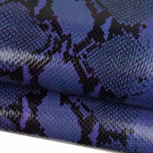 May include: Close-up of a textured, blue and black snakeskin pattern. The design features a scale-like texture with a gradient of dark blue to lighter blue hues, and black markings.