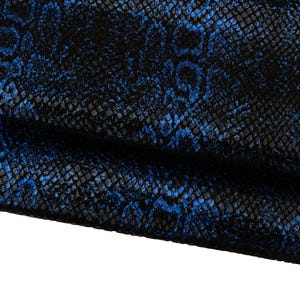 Peut inclure: Gros plan sur un tissu texturé avec un motif peau de serpent. Le tissu est principalement noir avec un motif bleu vif superposé. Le motif a l'apparence d'écailles.