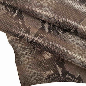 Könnte beinhalten: Nahaufnahme eines braunen und weißen Schlangenlederstoffs mit einem strukturierten Muster.