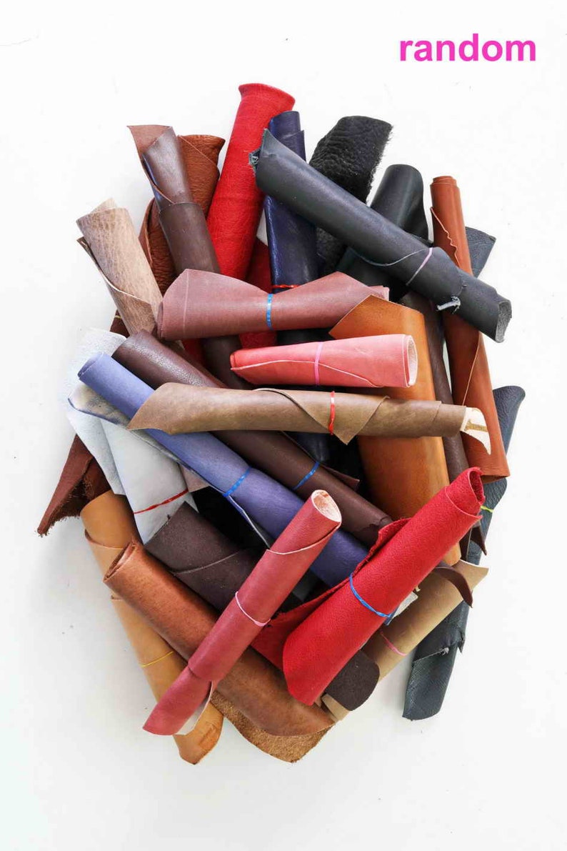 Pode incluir: Um monte de sobras de couro em v&aacute;rias cores, incluindo vermelho, marrom, bege e azul. O couro est&aacute; enrolado e amarrado com barbante.