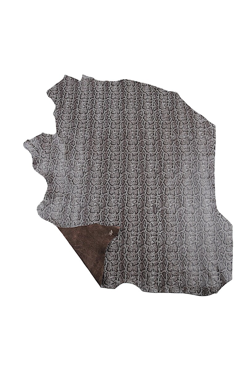 May include: A piece of grey leather with a snakeskin pattern. The leather has a textured surface and a dark brown underside. The edges of the leather are uneven, giving it a natural look. The leather is likely used for crafting.