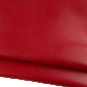 May include: Close-up of a vibrant red leather sheet. The material appears smooth and supple, with subtle variations in tone. The image highlights the rich color and texture of the leather, suitable for crafting or design projects.