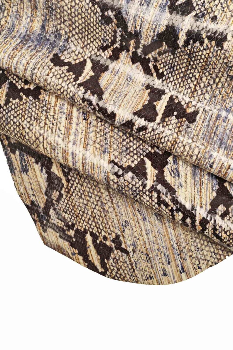 Op de afbeelding: Close-up van een bruine en witte slangenhuidstof met een textuurpatroon.