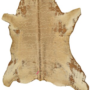 May include: A tan and brown cowhide rug with white stitching in a wavy pattern. The rug is approximately 3 feet by 4 feet.