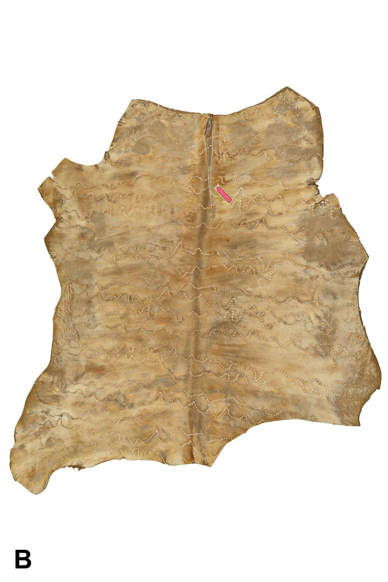 May include: A tan leather hide with a decorative stitching pattern. The stitching is done in a wavy line pattern.