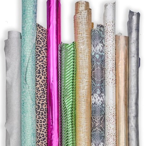 Op de afbeelding: Een verzameling opgerolde stofstalen in verschillende kleuren en patronen. Inclusief zilver, blauwgroen, luipaardprint, felroze, groen met diagonale strepen, goud, slangenprint, wit met gouden sterren en bruin. Ideaal voor knutsel- of designprojecten.