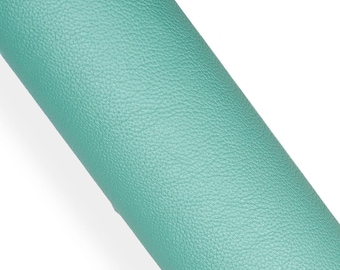 May include: A close-up of a rolled piece of teal-colored leather. The leather has a textured surface with a subtle grain pattern. The roll is positioned diagonally against a white background, highlighting the color and texture.