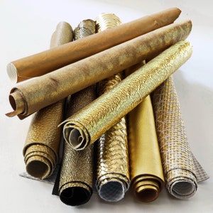 Könnte beinhalten: Eine Sammlung von acht Rollen goldfarbenem Leder, jede mit einer anderen Textur und einem anderen Muster. Die Rollen sind in einem Stapel angeordnet, wobei sich einige überlappen.