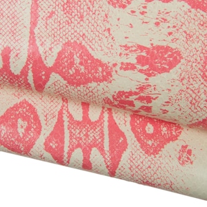 Puede incluir: Primer plano de un material texturizado blanquecino con un patrón repetitivo de formas abstractas rosas. El patrón se asemeja a un diseño de piel de serpiente. El material está doblado, revelando la textura y las variaciones de color.