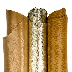 Może przedstawiać: Zbliżenie na trzy rolki teksturowanej skóry w odcieniach złota. Skóra ma metaliczny połysk i wzór przypominający gada. Rolki są ciasno zwinięte, prezentując elastyczność i fakturę materiału.