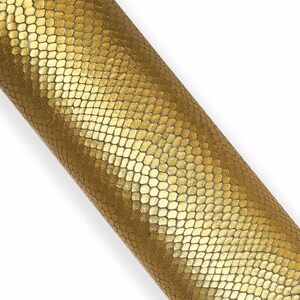 Op de afbeelding: Een rol goudkleurig imitatieleer met een textuur, schubachtig patroon. Het materiaal heeft een metallic glans en een honingraatontwerp, geschikt voor knutsel- of stoffeerprojecten.