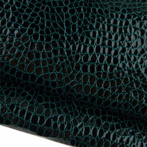 Può includere: Un materiale verde scuro con una superficie lucida, in rilievo e strutturata che imita l'aspetto delle squame di rettile. Il motivo è costituito da piccole forme arrotondate e interconnesse in una profonda tonalità smeraldo con linee nere.