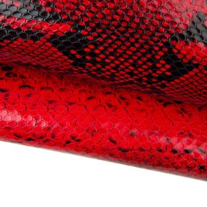 Puede incluir: Primer plano de una textura de piel de serpiente roja y negra. La piel de serpiente tiene un patrón de escamas con un acabado brillante. El color rojo domina la imagen, con acentos negros que crean un patrón contrastante. El material parece estar doblado.