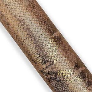 Könnte beinhalten: Ein gerolltes Stück Kunstleder mit Schlangenmuster. Das Material hat ein metallisches Gold- und Braunschema mit einem strukturierten, schuppenartigen Design. Das Material ist diagonal vor einem weißen Hintergrund abgewinkelt.