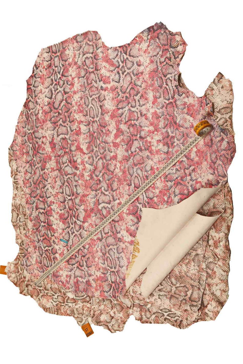 Peut inclure: Une grande pi&egrave;ce de cuir de peau de serpent avec un motif de peau de serpent rouge et marron. Un m&egrave;tre ruban et une &eacute;tiquette sont visibles sur le cuir. Le dessous du cuir est de couleur beige clair.