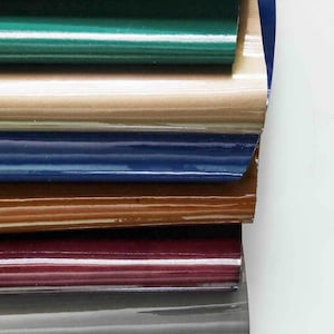 May include: A stack of eight different colored leather samples. The colors are: yellow, green, beige, blue, brown, burgundy, gray, and black.