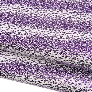 May include: A sheet of textured material featuring a repeating pattern of small, irregular purple spots against a white background. The surface has a slightly raised, granular appearance with a consistent distribution of the purple leopard-like print.