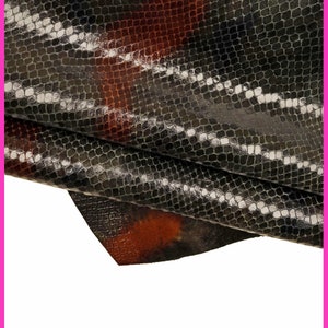 Puede incluir: Primer plano de un trozo de cuero de serpiente negro y marrón con un patrón texturizado.