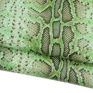 Puede incluir: Primer plano de un patrón de piel de serpiente texturizado en tonos verdes y negros. La piel de reptil tiene una apariencia escamosa, con una mezcla de tonos verdes claros y oscuros. El patrón es detallado e intrincado, con una sensación natural y orgánica.