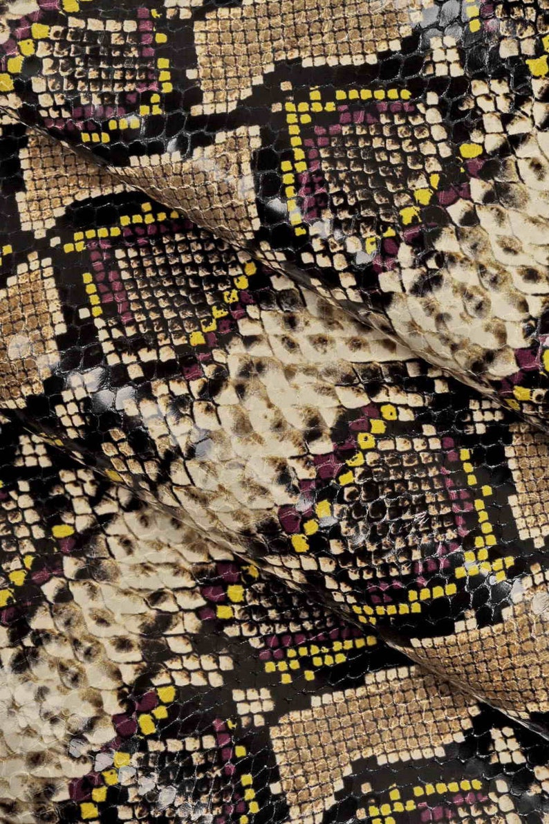 Pode incluir: Close-up de um tecido de pele de cobra com um padr&atilde;o de quadrados pretos, marrons, amarelos e roxos.