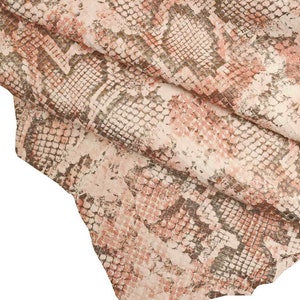 Peut inclure: Gros plan sur un morceau de cuir avec un motif peau de serpent. Les couleurs sont principalement blanc, rose et marron. Le texte "bianco/rosa/fucile" est au bas de l'image.