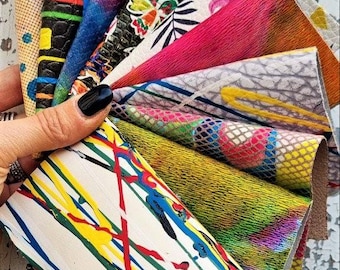 May include: A selection of patterned leather swatches, showcasing a variety of designs and textures. The samples feature geometric, floral, and abstract patterns, with a colour palette including bright pinks, greens, and deep blues and blacks. The leather is held in a hand.
