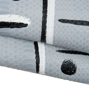 May include: Close-up of a textured, grey surface with a scale-like pattern. The design features black and white brushstrokes, including vertical stripes and circular shapes. The overall aesthetic is abstract and artistic.