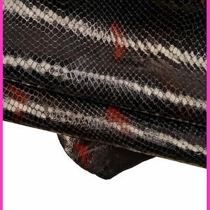 Peut inclure: Cuir de serpent noir et rouge avec un motif texturé. Le cuir est plié sur lui-même, créant un effet dramatique.