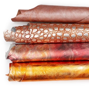 Pode incluir: Quatro rolos empilhados de material texturizado. O rolo superior é castanho claro com um padrão fino de diamante. O segundo é de cobre metálico com uma textura de escamas. O terceiro é marmoreado em vermelho e laranja. O inferior é dourado brilhante.