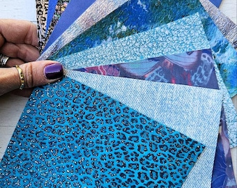 May include: A collection of blue and teal patterned fabric swatches with glitter, including a leopard print, a cracked ice design, and a denim-like pattern.