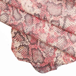 Peut inclure: Gros plan sur un morceau de cuir avec un motif peau de serpent. Le cuir pr&eacute;sente un m&eacute;lange de rose, de blanc et de gris fonc&eacute;. Le texte "bianco/fuxia/viola" est au bas de l'image.