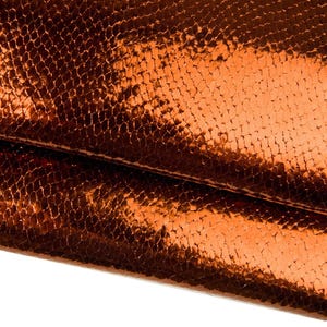 Op de afbeelding: Close-up van een getextureerd, metallic oranje materiaal. Het oppervlak heeft een schubbenachtig patroon, met een glanzende afwerking die licht reflecteert. De kleur is een warm, roodachtig oranje, met donkere gebieden die diepte creëren.