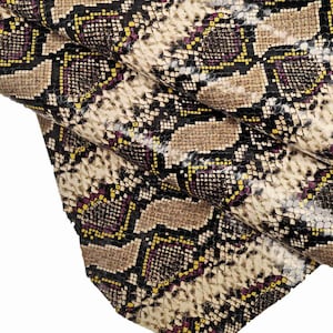 Pode incluir: Close-up de um tecido de pele de cobra com um padr&atilde;o preto, amarelo e roxo. O tecido tem um acabamento brilhante.