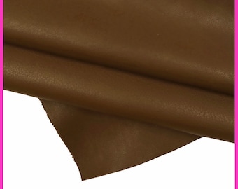 May include: A close-up of a brown leather fabric with a textured surface. The fabric is folded over itself, showing the inside of the material.