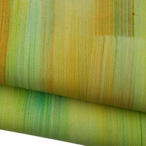Op de afbeelding: Close-up van een stof met een getextureerd oppervlak. De stof heeft verticale strepen in geel, oranje en groen, waardoor een levendig, abstract patroon ontstaat. De stof is dubbelgevouwen, waardoor de onderkant zichtbaar is.
