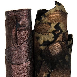 Może przedstawiać: Dwie rolki materiału. Jedna ma błyszczący, ciemnobrązowo-czerwony kolor. Druga ma wzór kamuflażu w odcieniach brązu, czerni i oliwkowej zieleni. Tkanina wydaje się mieć metaliczny połysk.